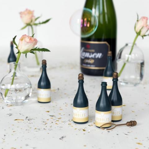 Celebration bottle bubbles on a table in front of a bottle of champagne