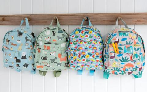 Four children's backpacks on a wooden wall hook