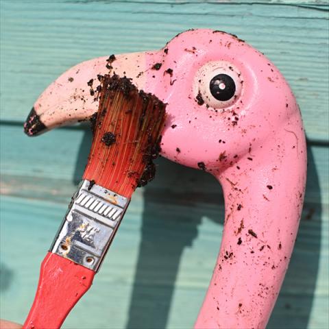 A pink flamingo is painted with a muddy paintbrush