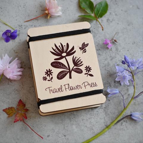 A travel flower press surrounded by flowers