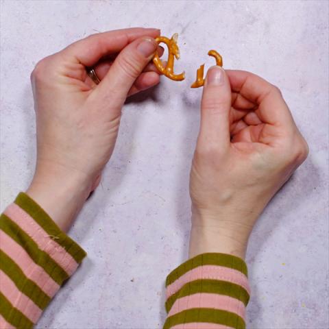 A pair of hands breaks a pretzel in half