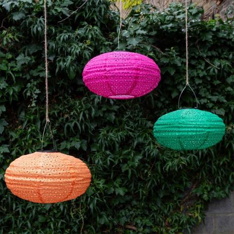 3 lanterns hanging in front of a garden bush