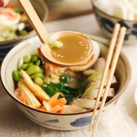 Ramen spoon holding broth over ramen