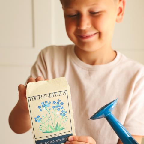 Boy smiling opening garden seed packet
