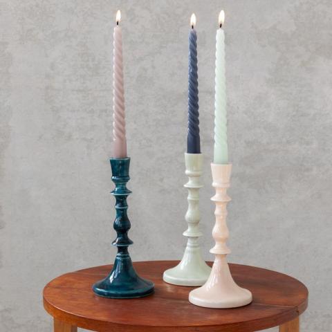 3 candlestick holders with lit candles on table