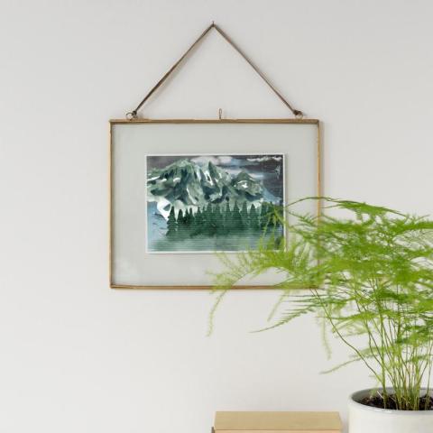 Gold frame hanging on wall next to plant