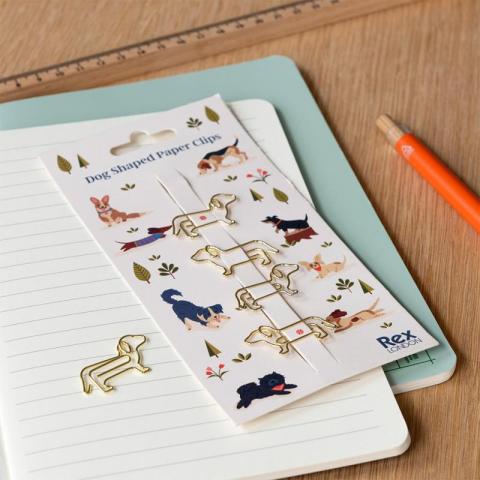 Dog shaped paper clips on notebook on wooden desk