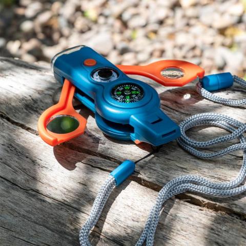 Blue and orange whistle placed on log outside