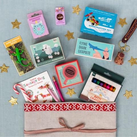 A blue tablecloth is laid with stocking fillers pouring from a Christmas stocking