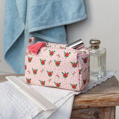 Rectangular makeup bag in pale pink with a floral pattern of small red and green flowers with tag