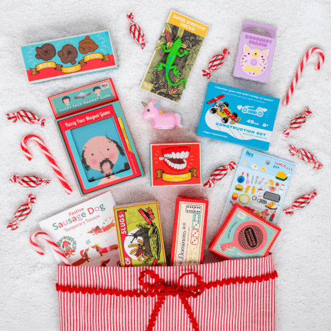 An array of stocking filler toys and games is spread out on a blue cloth