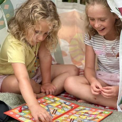 Two young girls playing with board game in a 'den'