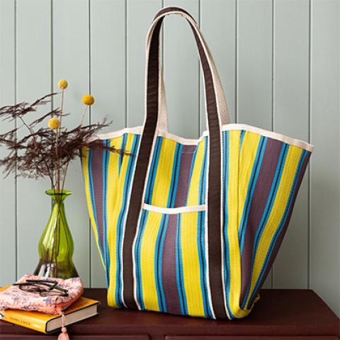 Yellow and blue stripe bag next to vase