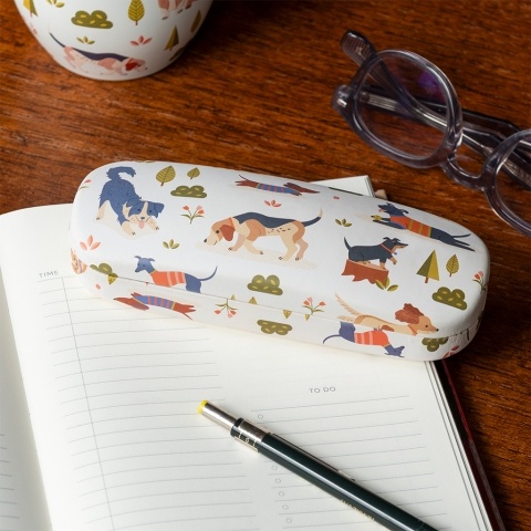 glasses case with playful dog illustrations resting on a notebook beside a pair of glasses.