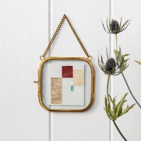 Gold hanging frame with green plant to right