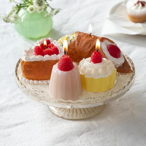 4 candles shaped like cakes, all on a cake serving tray