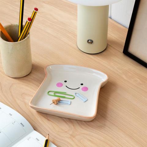 Toast shaped trinket tray with paper clips on wooden table