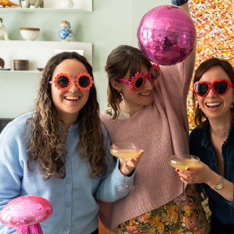 3 women with pink disco balls and sunglasses smiling