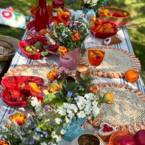 A table is laid with colourful tins, placemats, flowers, candles and bowls.