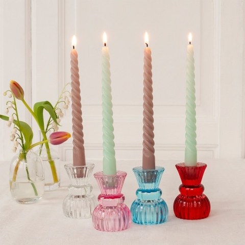 4 twisted candles next to flowers in vase