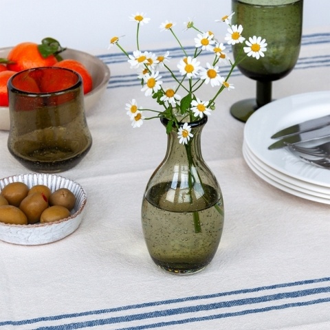 Olive green vase with daisies inside on table setting