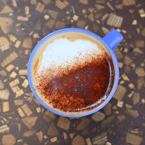 A top down shot of a blue mug with chocolate dusting on coffee