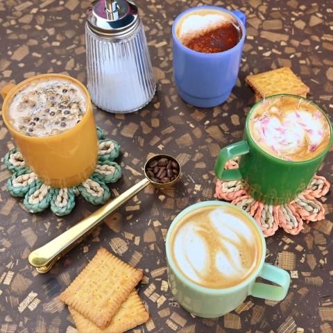 Four coffee cups each with decorations or latte art on top