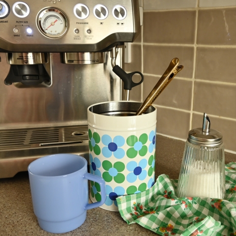 A floral canister sits next to a coffee machine