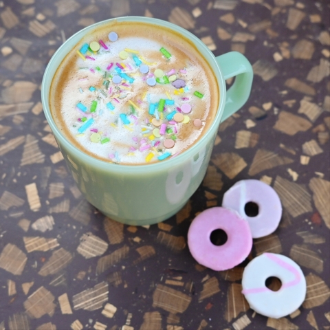 A mug of coffee with rainbow sprinkles on top