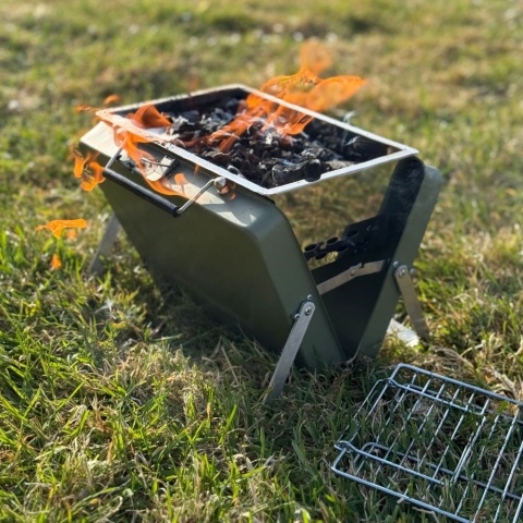A portable suitcase barbecue is filled with burning charcoal.