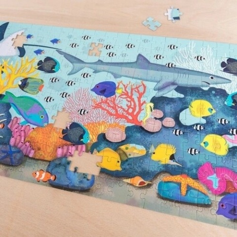 Coral reef jigsaw puzzle, partly completed, showing sharks, fish and coral illustrations.
