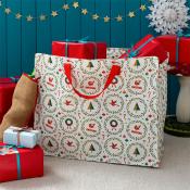 White festive shopping bag with red handles and Christmas-themed illustrations, placed among wrapped gifts.