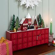 Red wooden advent calendar with numbered drawers, decorated with a miniature snowy village scene on top.