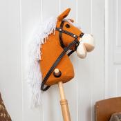 A toy hobby horse with an orange fabric head, white yarn mane, and black bridle mounted on a wooden stick.