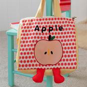 A colourful tote bag with a red polka-dot front panel featuring a cartoon apple illustration labelled ‘Apple.’