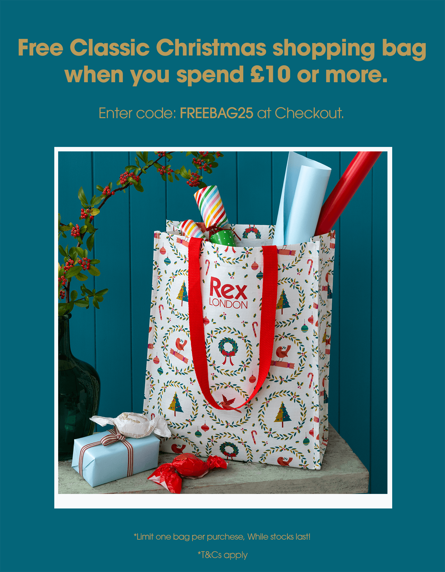 A festive gift bag with red handles and a holiday-themed pattern featuring wreaths, trees, and candy canes. The bag is labeled “Rex London” and filled with colorful wrapping paper and small gifts, placed on a wooden surface beside wrapped presents and candies.