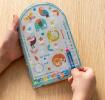 Child playing pinball game with colourful illustrations of wild animals on backing