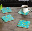 Four turquoise wood and cork coasters featuring cheetah pattern on table with drink