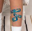 Dark blue plasters with print of fairies amongst flowers on child's leg
