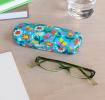 Light blue hardshell glasses case with print of butterflies amongst flowers on table