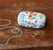White mini travel case with print of wild flowers with jewellery to fit inside