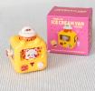 yellow wind up ice cream van with pink packaging box in background