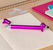 Pink sausage dog stylus ballpoint pen with cap off, lying on a notebook