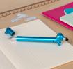 blue sausage dog stylus ballpoint pen with cap off, lying on a notebook