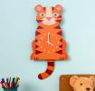 Tiger-shaped wooden wall clock in orange, featuring a white numbered dial with clock hands and a tail