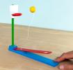 wooden tabletop basketball game with a lever launching a yellow ball toward a hoop