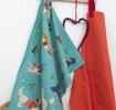 Cotton tea towel with colourful illustrations of dogs in winter clothing, hanging on hook