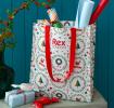 Christmas shopping bag with classic designs, filled with wrapping paper