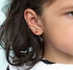 Stick-on earrings in cherry and lightning bolt shapes on a kid’s ear