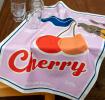 Cotton tea towel featuring a cherry print with pink background